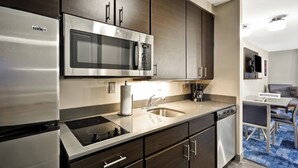 A modern kitchen with stainless steel appliances, dark wood cabinets, and a built-in microwave. - Towneplace Suites Dover Rockaway (Dover)