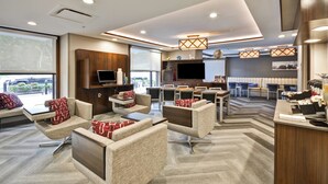 A modern living room with sofas, a coffee table, and a TV. There is a kitchen area with a dining table and chairs. - Towneplace Suites Dover Rockaway (Dover)