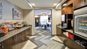 A modern kitchen with a herringbone floor pattern, stainless steel appliances, and a buffet setup with various food items. - Towneplace Suites Dover Rockaway (Dover)