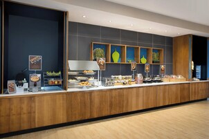 Una barra de desayuno moderna con diversas opciones de comida, como pasteles, frutas y bebidas.