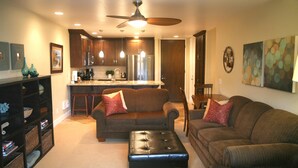 A modern living room with a sofa, ottoman, and a dining area with a table and chairs. - Luxury on the Beach (Oceanside)