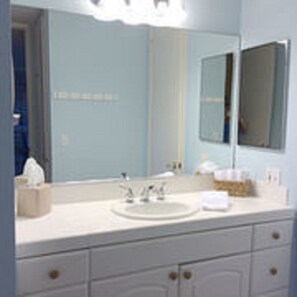 A bathroom with a sink, mirror, and cabinets. - Paradise Found (Oceanside)