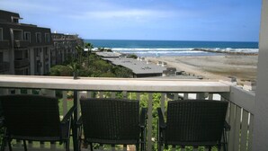 Ein Balkon mit Korbstühlen mit Blick auf Strand und Meer.