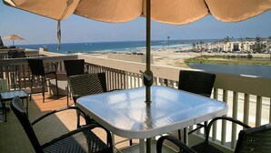 Una terraza con mobiliario exterior, vistas a la playa y una piscina.