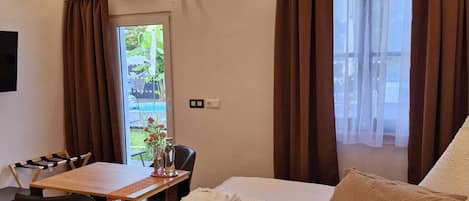 Habitación de hotel con una cama grande, un escritorio de madera y vistas a zonas verdes.