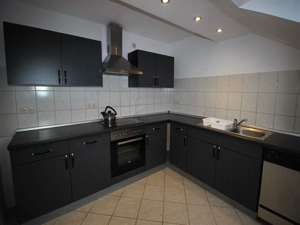A modern kitchen with dark cabinets, a stainless steel sink, and a built-in oven.