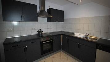 A modern kitchen with dark cabinets, a stainless steel sink, and a built-in oven.
