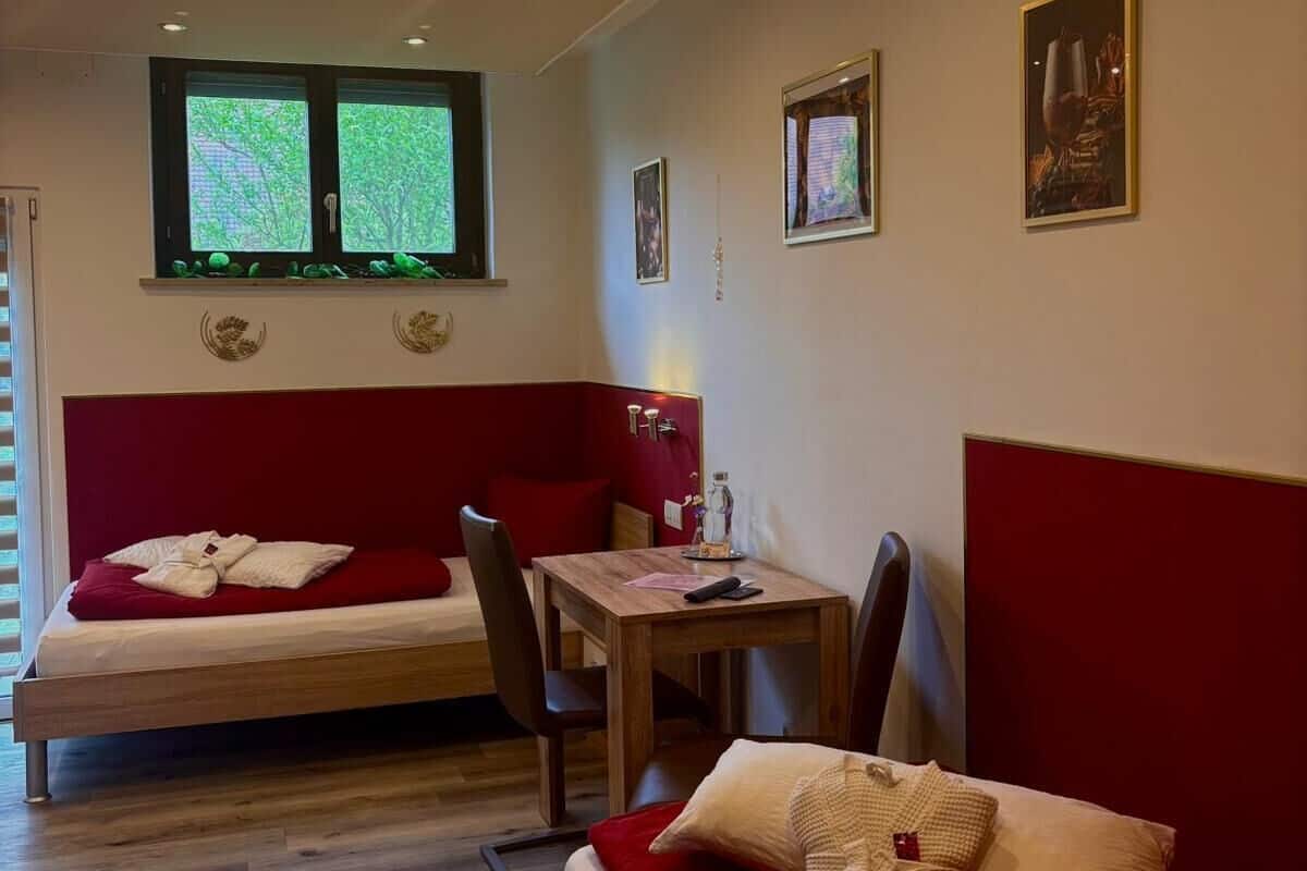 Ein Zimmer mit einem Bett, einem Schreibtisch und zwei Fenstern.