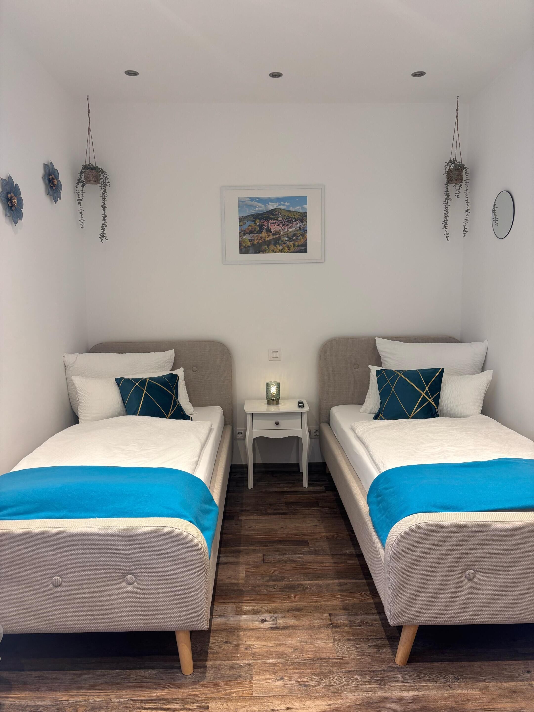 Habitació doble amb dos llits, una petita taula de nit amb una làmpada, i un quadre al mur.