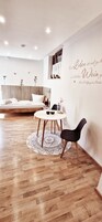 Un dormitorio moderno con cabecera de madera, una mesa redonda de comedor con dos sillas y una pared decorativa con una cita.