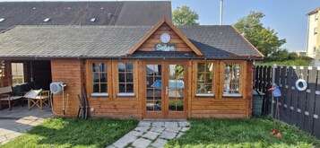 Una cabaña de madera con techo de tejas, puerta de madera y ventanas grandes.