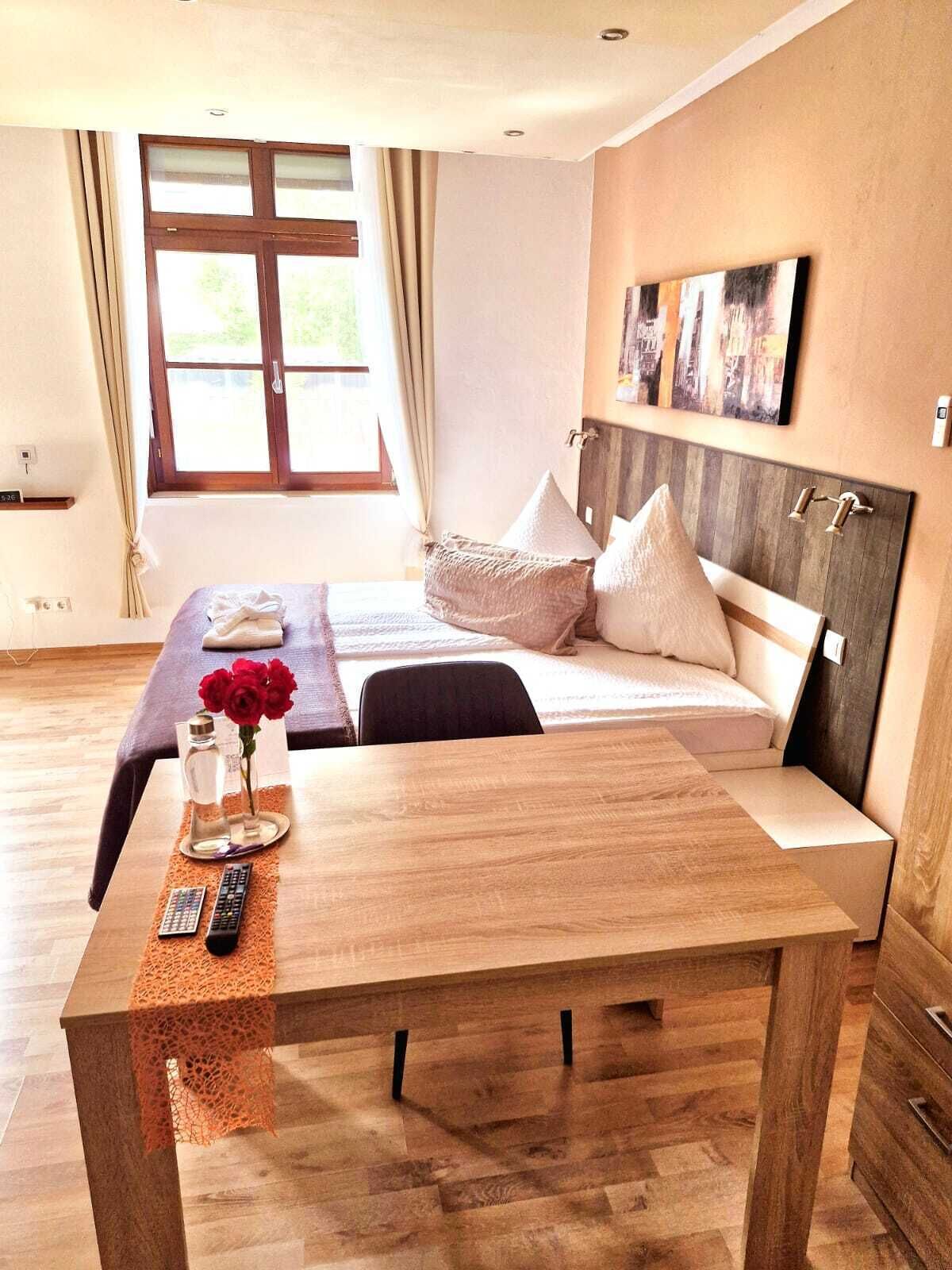Habitación de hotel con cama, una mesa de madera y una ventana con cortinas.