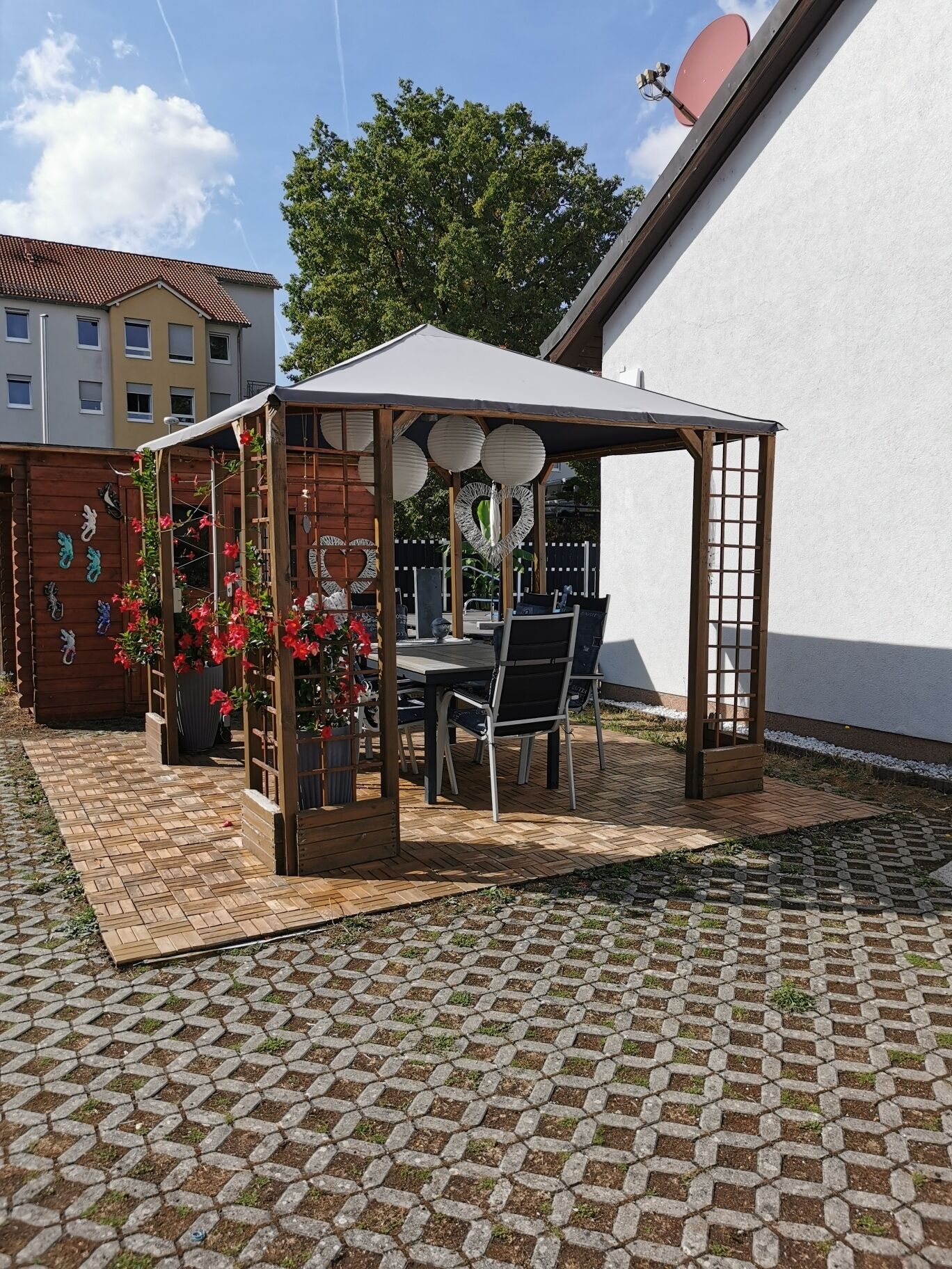 Ein Patio mit einer Holz-Pergola, einem Tisch, Stühlen und Topfpflanzen.