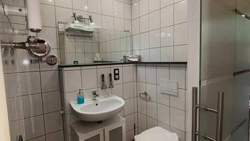 Een moderne badkamer met een glazen douchecabine, een wit wastafelmeubel en een toilet.