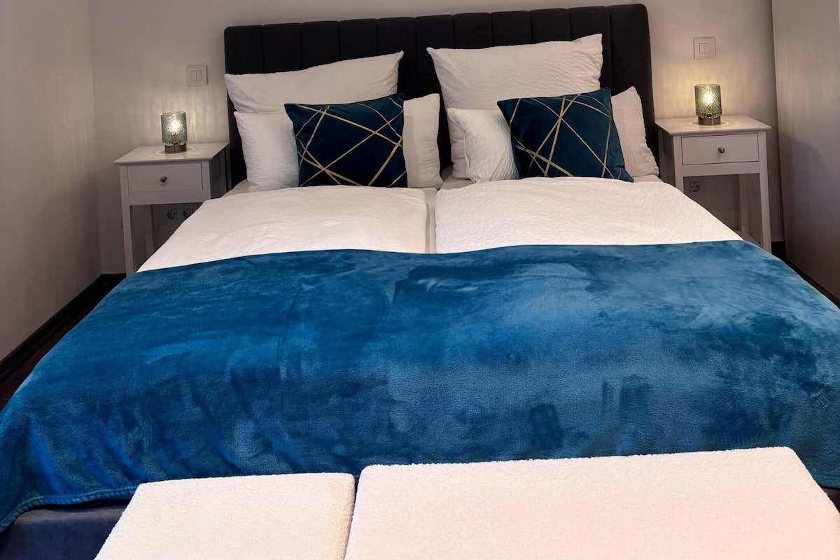 Ein Schlafzimmer mit einem großen Bett, zwei Nachttischen und einem Beistelltisch mit einer Lampe.