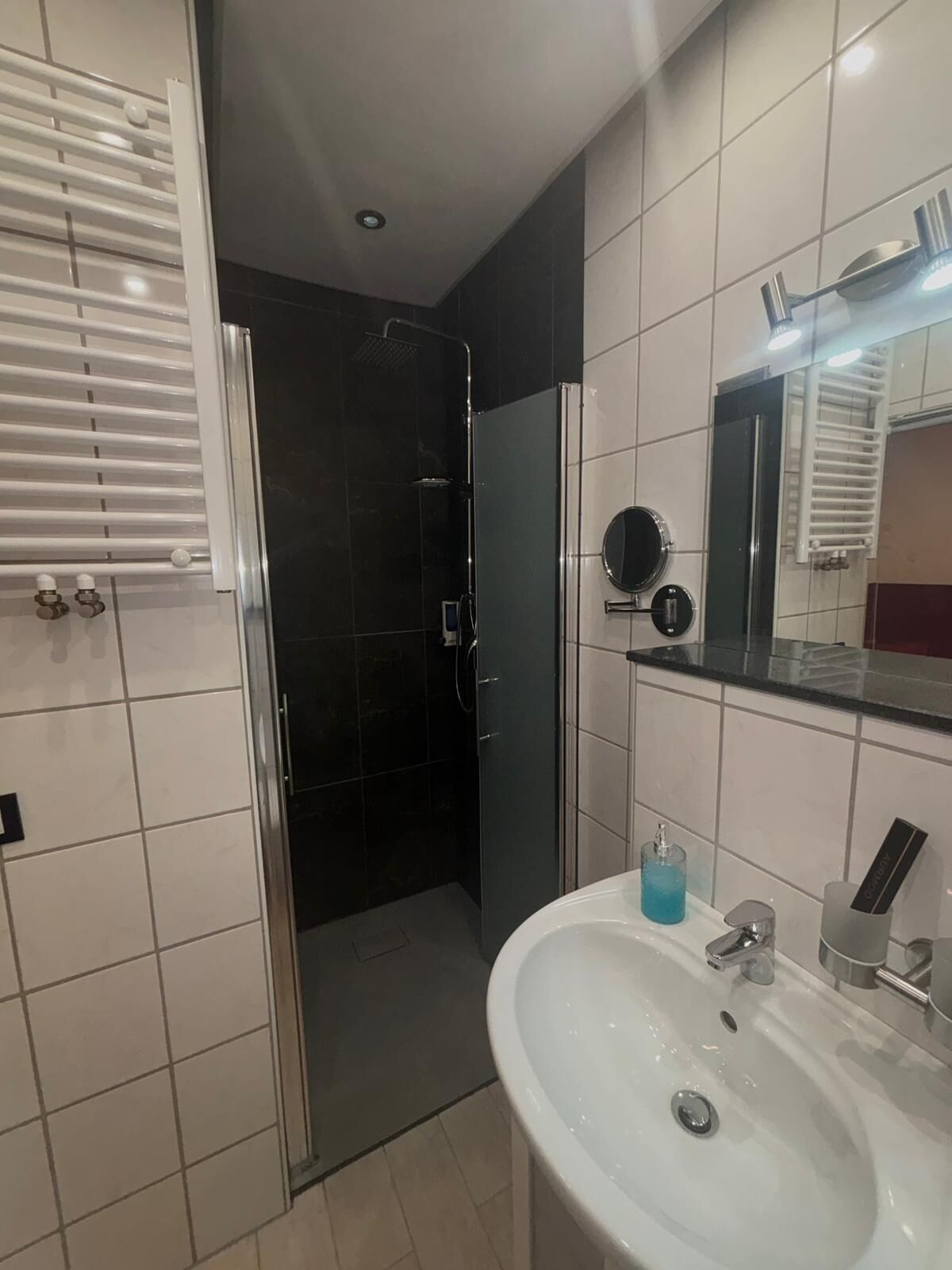 Un baño moderno con ducha, lavamanos y espejo.