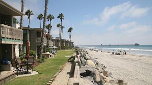 A beachfront hotel with a patio area, palm trees, and a view of the ocean. - Steps to the Sand (Oceanside)