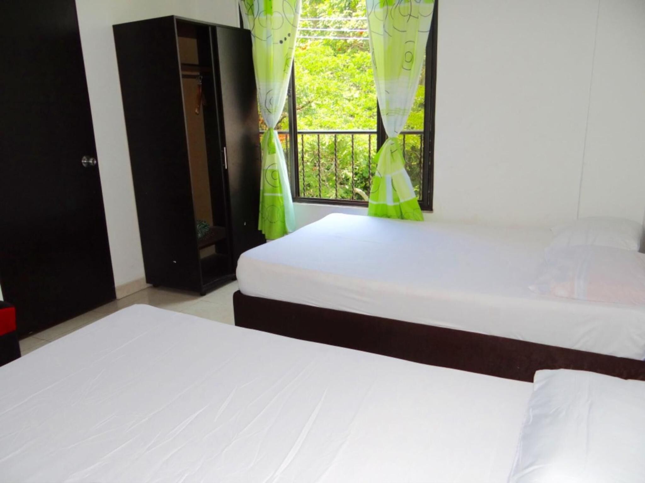 Habitación con dos camas, un armario y una ventana con cortinas.