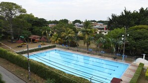 A rectangular swimming pool with clear blue water, surrounded by a fence and palm trees. - Casa Santiago Mayor (Cali)