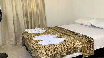 A hotel room with a bed, a curtain, and a floor lamp.