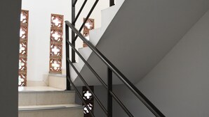 A staircase with beige steps and black railings, leading to a landing with a white wall and decorative panels. - Casa Santiago Mayor (Cali)