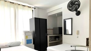 A hotel room with two beds, a refrigerator, a microwave, a sink, a mirror, and a wall-mounted fan. - Casa Santiago Mayor (Cali)