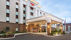 A modern hotel with a 'Welcome' sign, a covered entrance, and an American flag. - Hampton Inn North Olmsted Cleveland Airport (North Olmsted)