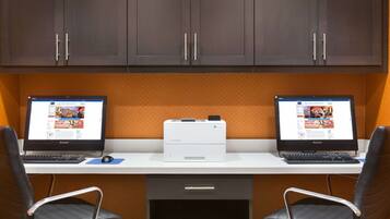 A workspace with two laptops, a printer, and two chairs.