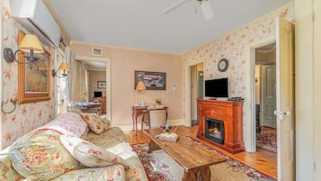 A living room with a sofa, a wooden coffee table, a fireplace, and a television.