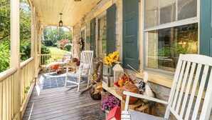 Une véranda avec des fauteuils à bascule, une table agrémentée d’objets décoratifs et une vue sur le jardin.