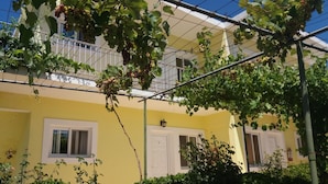 A yellow building with a balcony, a window, and a door. - Amadeus Hawaii Studios Apts (Corfu)