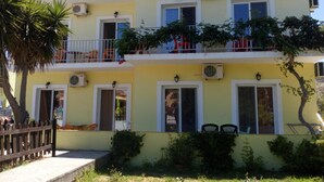 A two-story building with balconies, air conditioning units, and a wooden fence. - Amadeus Hawaii Studios Apts (Corfu)