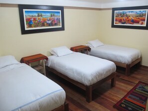 A room with three single beds, wooden headboards, and a colorful rug. - Tumy House B&B (Ollantaytambo)