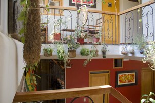 Un interior de varios niveles con balcones, plantas en macetas y barandilla de madera.