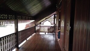A covered wooden corridor with a metal railing, leading to a staircase. - Bayu Beach Penarek (Setiu)