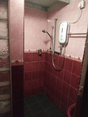 A small, tiled shower room with a handheld showerhead and a wall-mounted control panel. - Bayu Beach Penarek (Setiu)