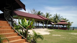 A beachside resort with a staircase leading to a covered area, palm trees, and a view of the ocean. - Bayu Beach Penarek (Setiu)