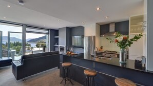 A modern kitchen with a large island, bar stools, and a view of mountains. - Villa Two at Vailmont Queenstown (Queenstown)