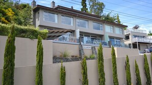 A modern two-story house with a balcony and a stone wall. - Villa Two at Vailmont Queenstown (Queenstown)