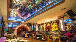 A modern lounge area with a geometric patterned floor, plush seating, and decorative lighting.