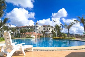 A swimming pool with lounge chairs, a large building with a dome, and palm trees. - Yang Jiang Country Garden Phoenix Hotel (Yangjiang)