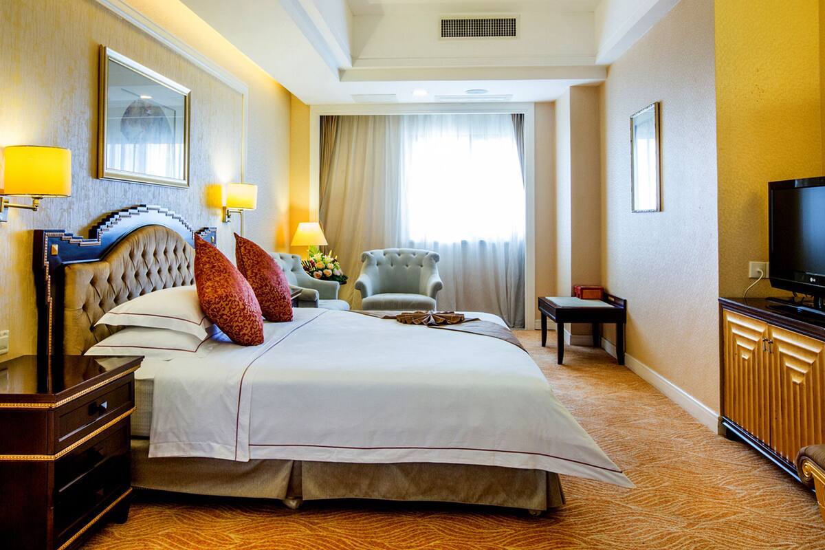 A hotel room with a large bed, a television, a chair, and a desk.