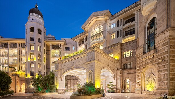 A historic building with a prominent tower, large arched entrance, and multiple balconies.