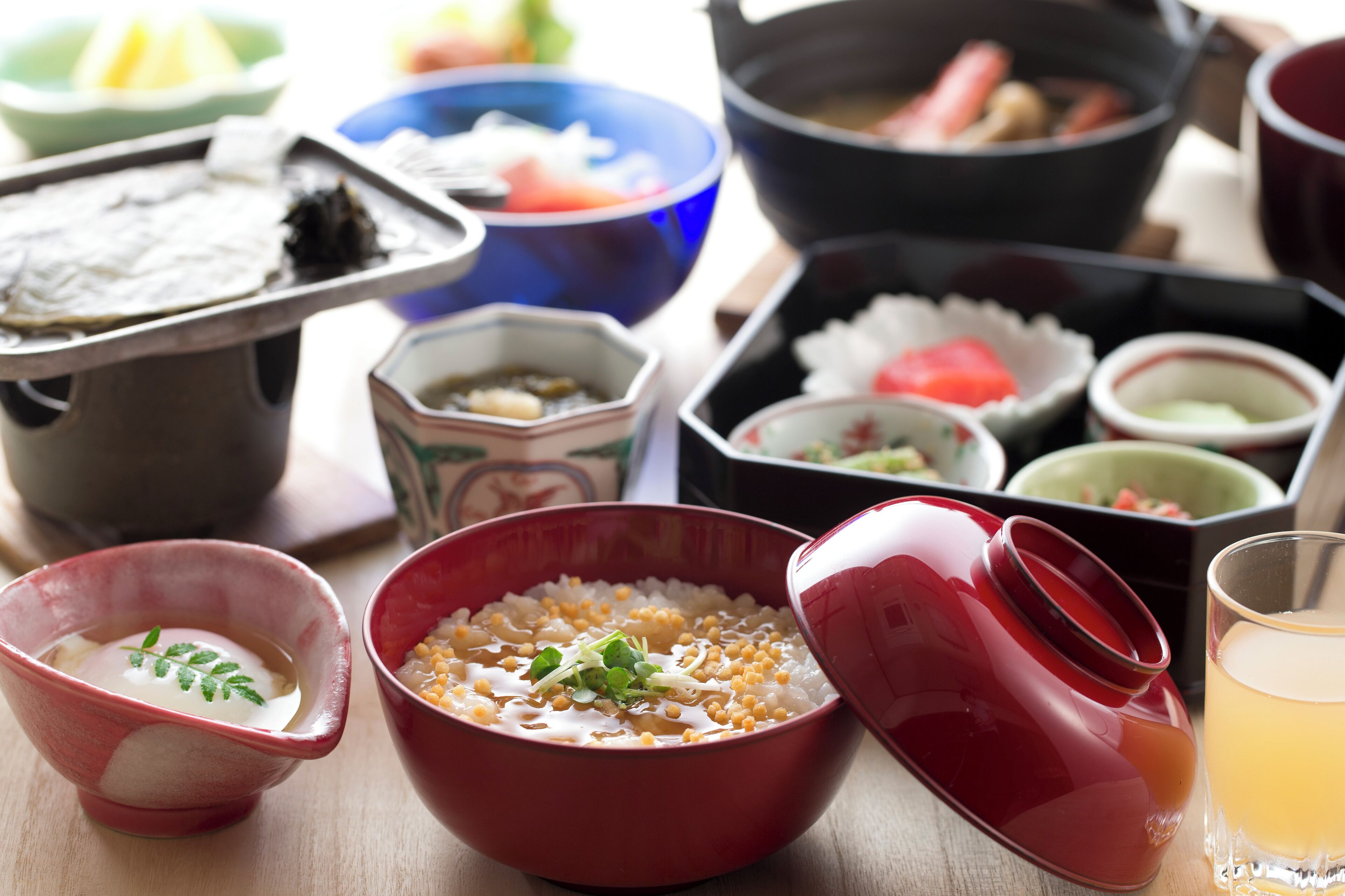 A variety of traditional Japanese dishes including a bowl of rice, a bowl of soup, and several small dishes with different ingredients.
