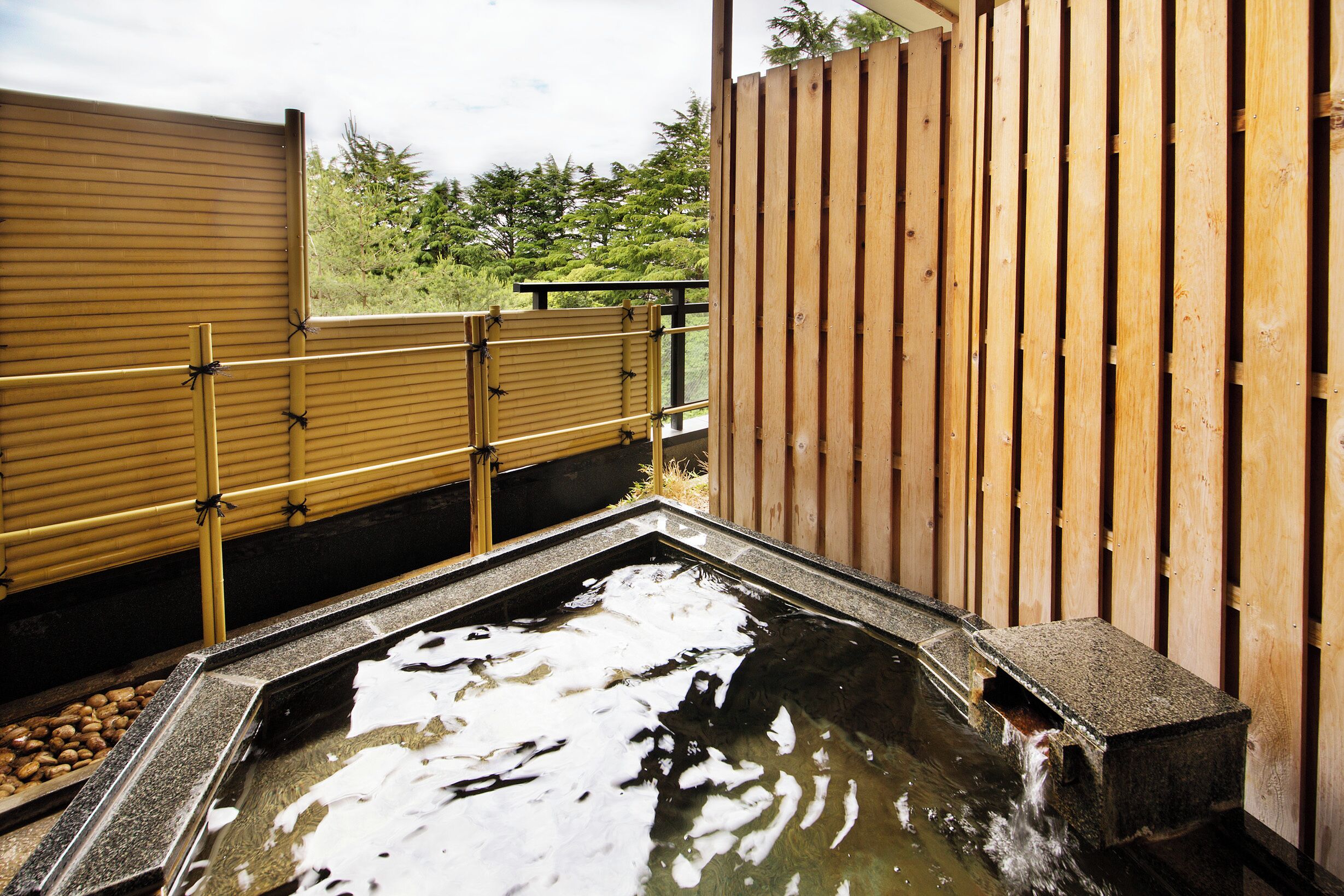 Een traditionele Japanse onsen met een houten omheining en een stenen bassin.