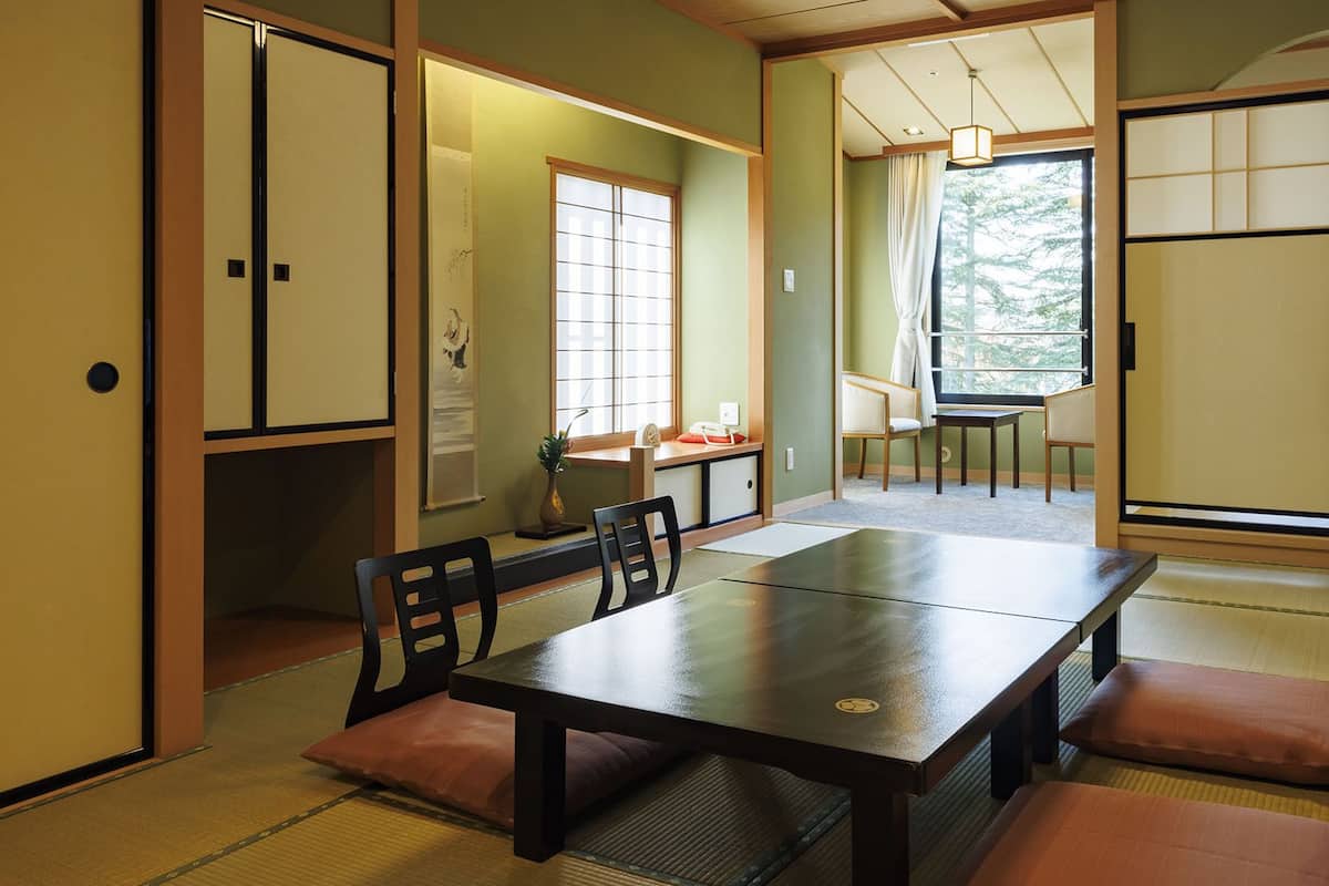 Ein traditioneller japanischer Raum mit Tatami-Boden, einem niedrigen Tisch und gleitenden Schiebetüren.