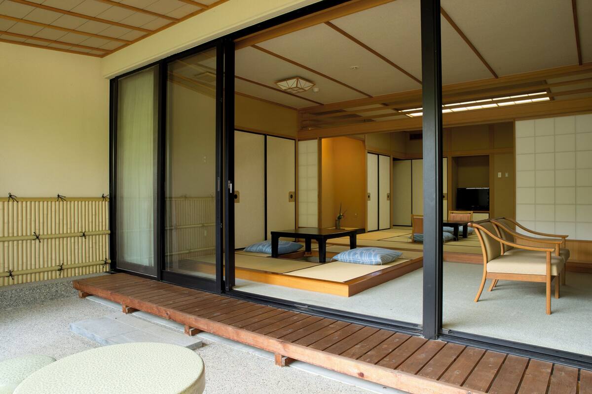 A traditional Japanese room with tatami flooring, sliding doors, and a low wooden platform.