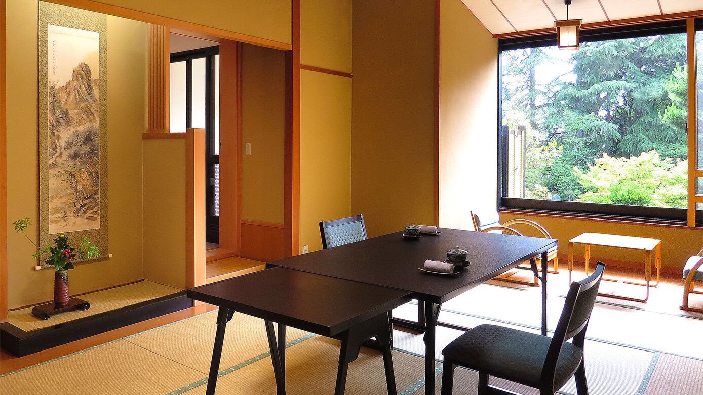 Una habitación japonesa tradicional con suelo de tatami, una mesa baja y sillas.
