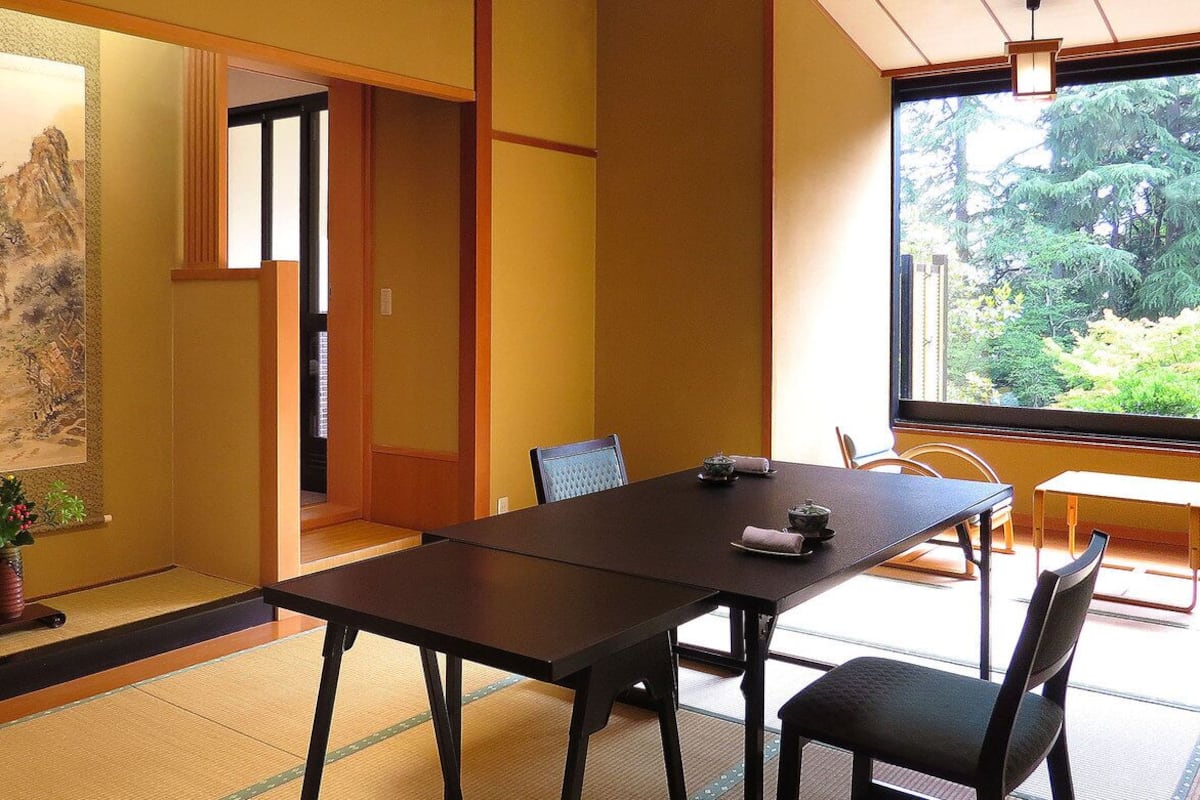 A traditional Japanese room with tatami flooring, a low table, and chairs.