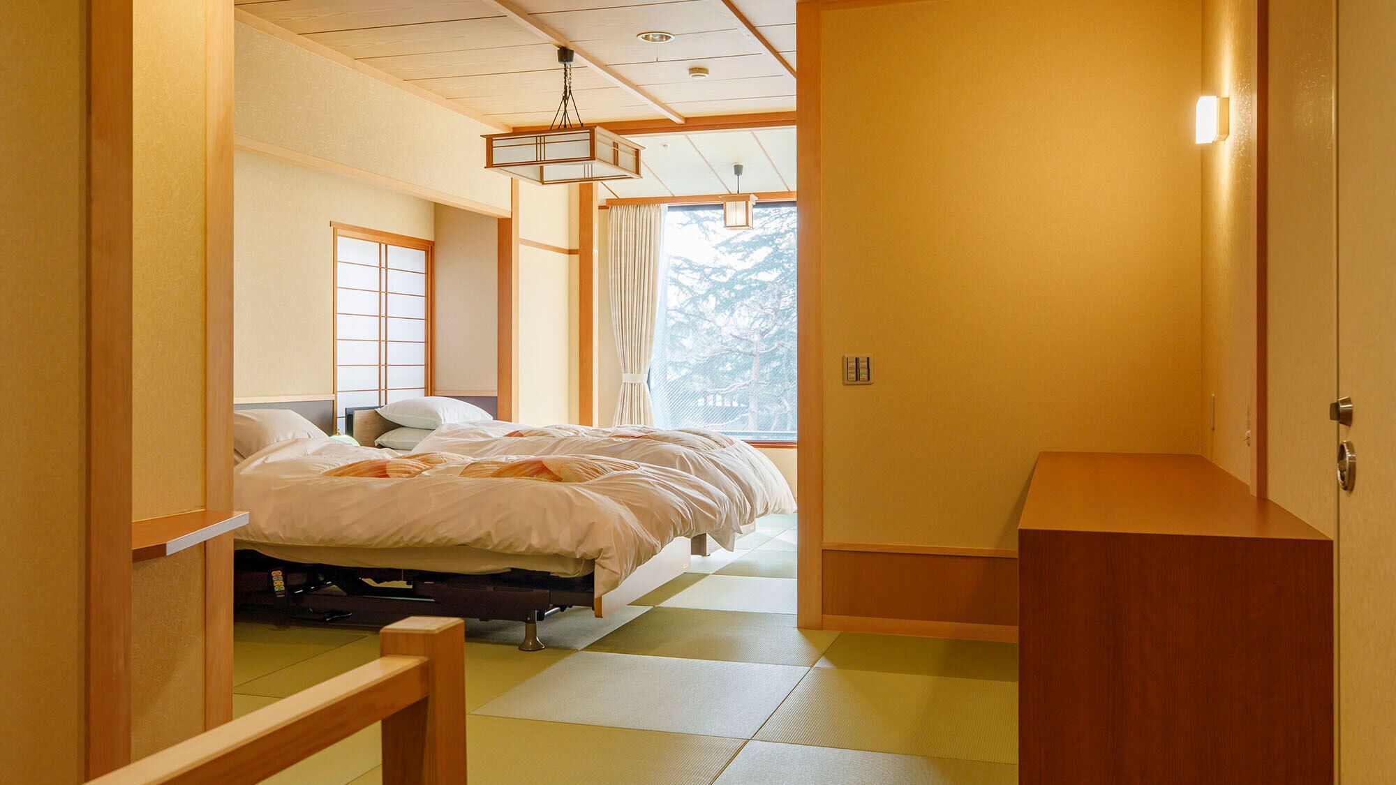 Una habitación tradicional japonesa con suelo de tatami, una cama con ropa de cama blanca, un escritorio de madera y un puertas correderas.